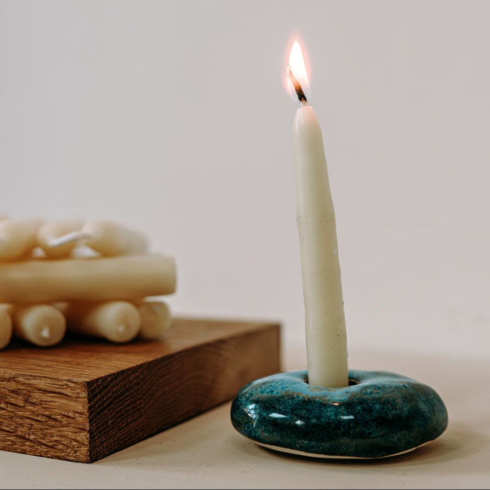 Candle in a green ceramic holder with a plain background