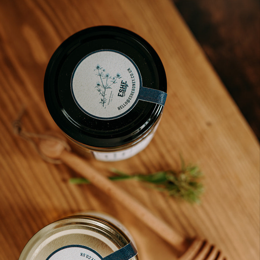 Two jars of honey with labels on a wooden surface