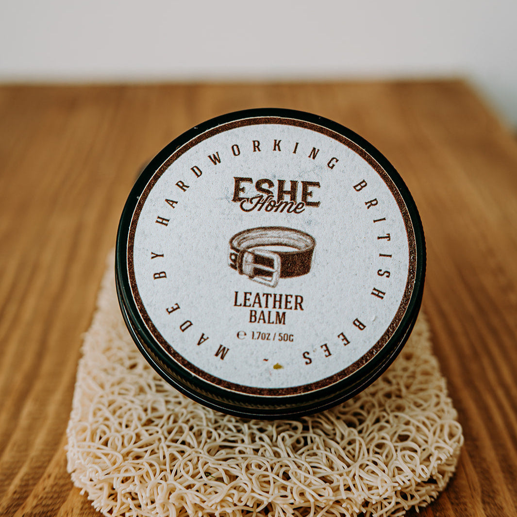 Jar of leather balm with 'Eshe Home' branding on a wooden surface