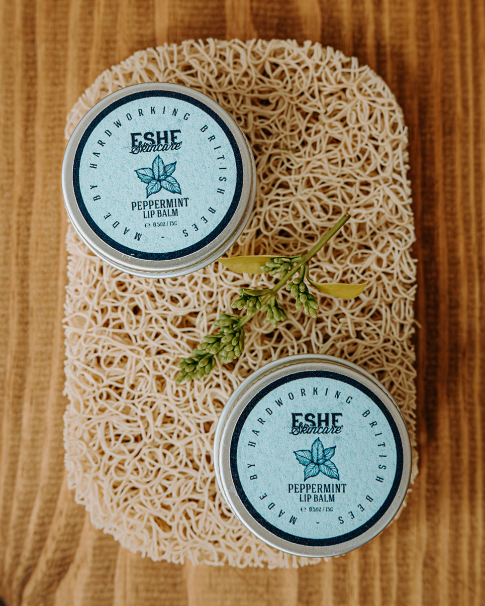 Two Eshe Peppermint Lip Balm on a wooden surface.