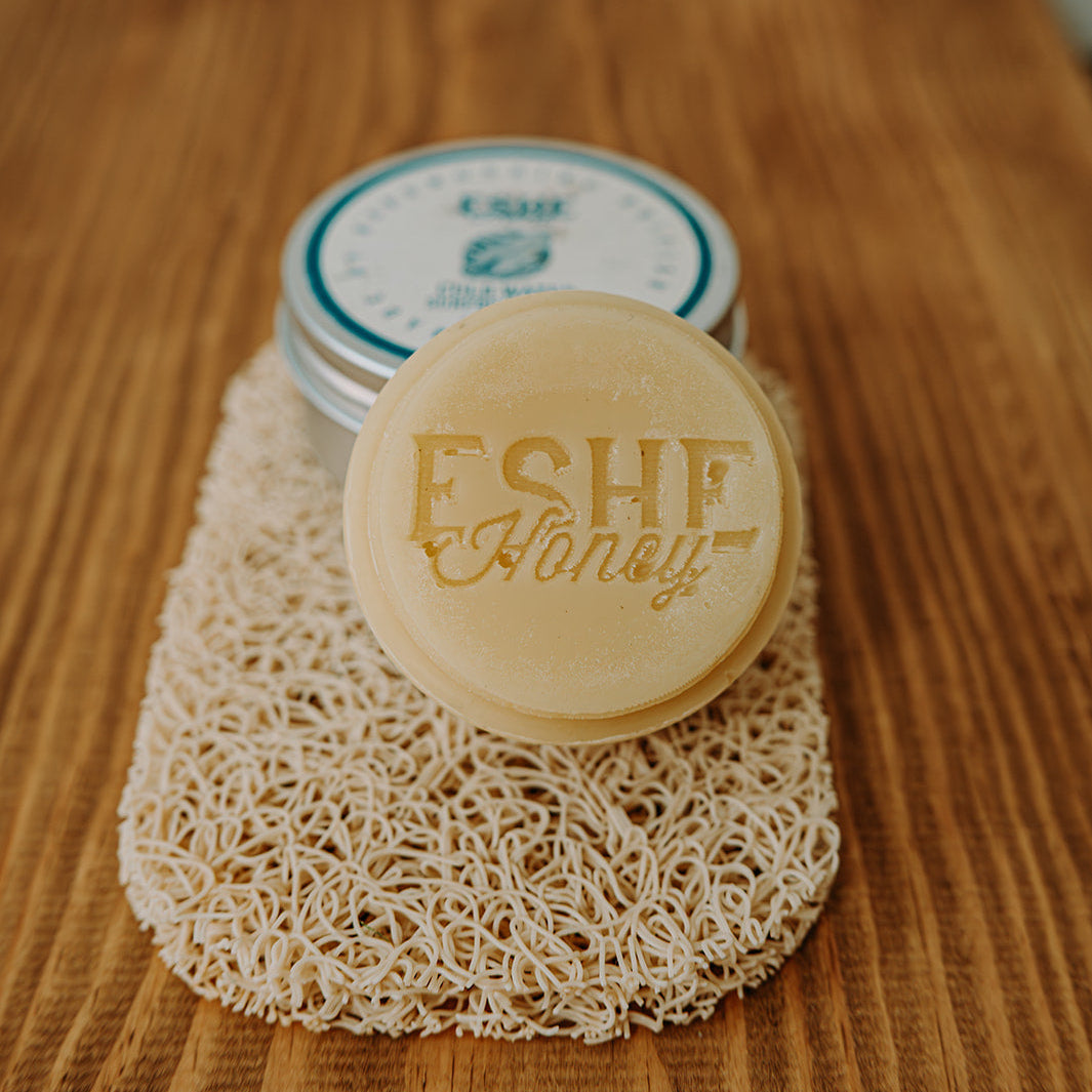 Disc of surfboard wax with 'Eshe Honey' branding on a wooden surface
