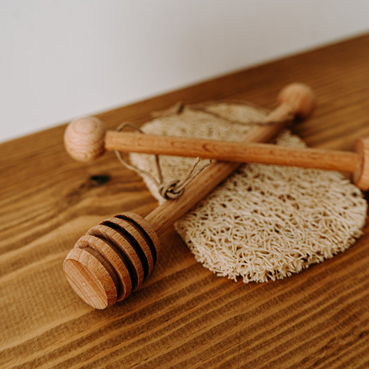 Wooden honey dipper with a honeycomb on a wooden surface