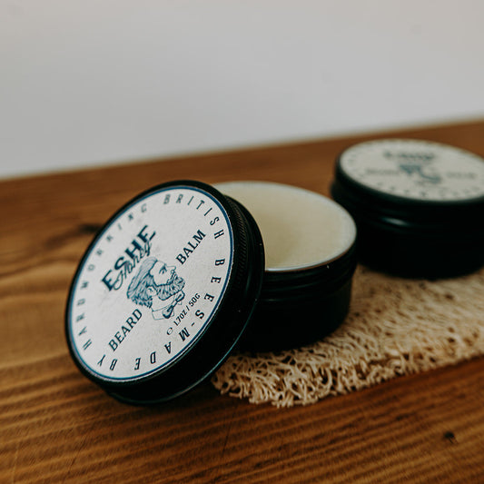 Two containers of Eshe Beard Balm on a wooden surface with a white background