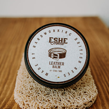 Jar of leather balm with 'Eshe Home' branding on a wooden surface