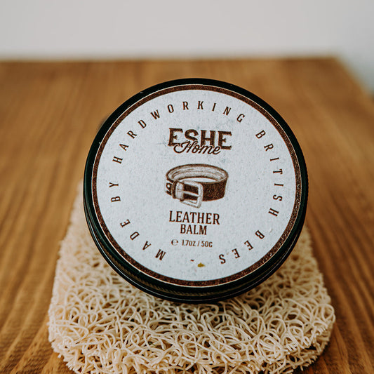 Jar of leather balm with 'Eshe Home' branding on a wooden surface