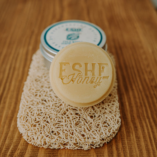 Disc of surfboard wax with 'Eshe Honey' branding on a wooden surface